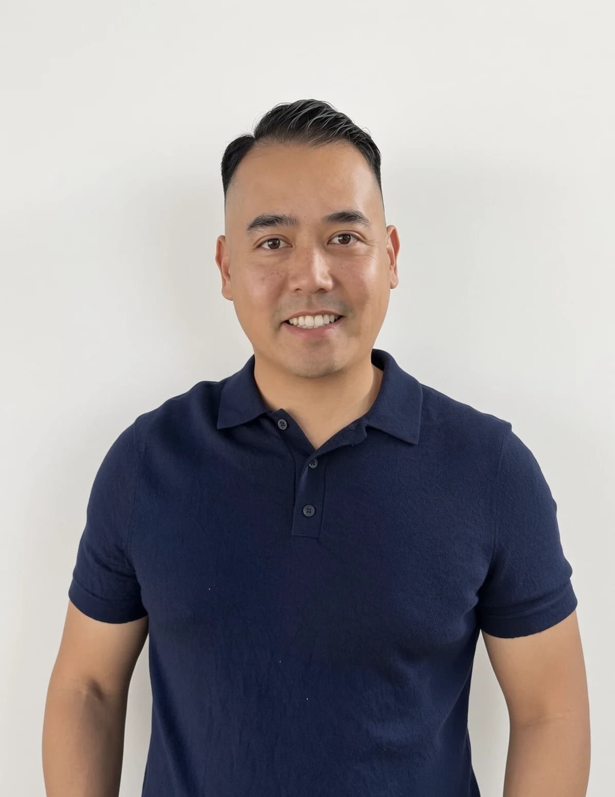 Stanley Yang smiling in a navy polo shirt